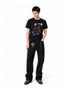 Full body shot of model wearing a black waffle knit graphic tee styled with dark wide-leg jeans.