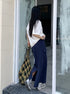 Model enters glass doorway wearing navy drawstring maxi skirt with side pockets and oversized tee.