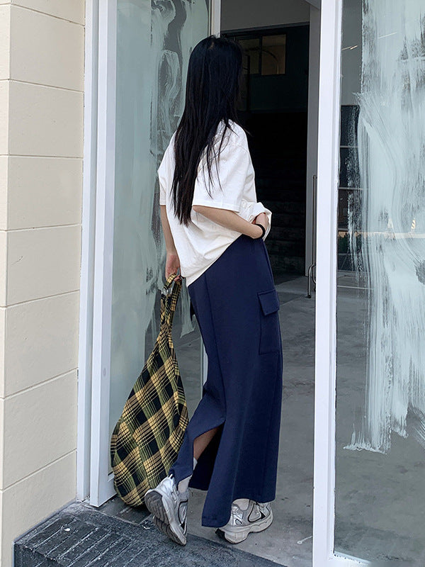 Model enters glass doorway wearing navy drawstring maxi skirt with side pockets and oversized tee.