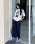 Model poses at doorway in navy maxi skirt with cargo pockets, graphic tee, and chunky sneakers.