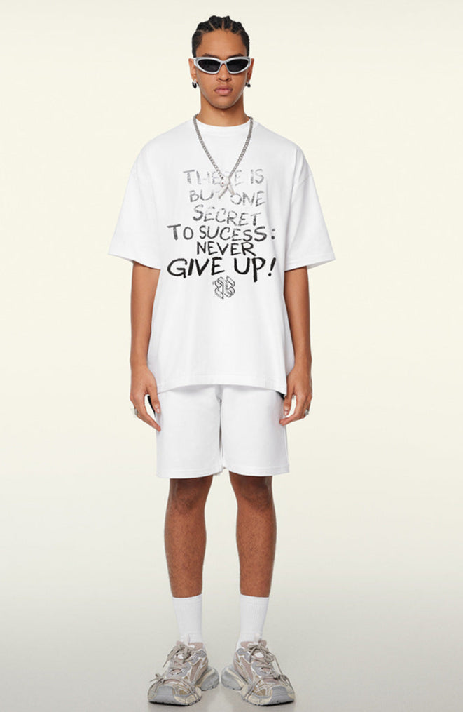 Model in white oversized tee with 'Never Give Up' text, standing front-facing