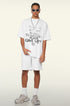 Model in white oversized tee with graphic text, one hand in pocket