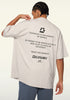 Model adjusting collar while showing back text on cream tee.