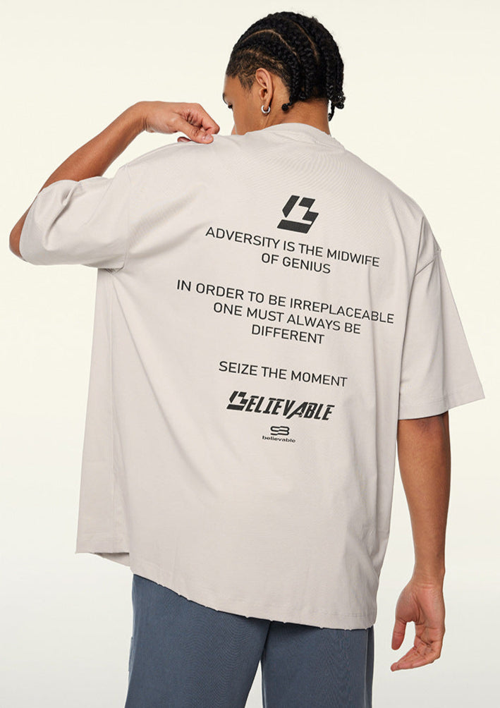 Model adjusting collar while showing back text on cream tee.