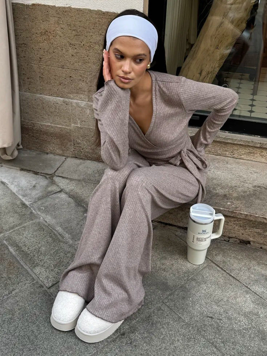 Woman in a oatmeal outfit sitting on steps with a tumbler. 