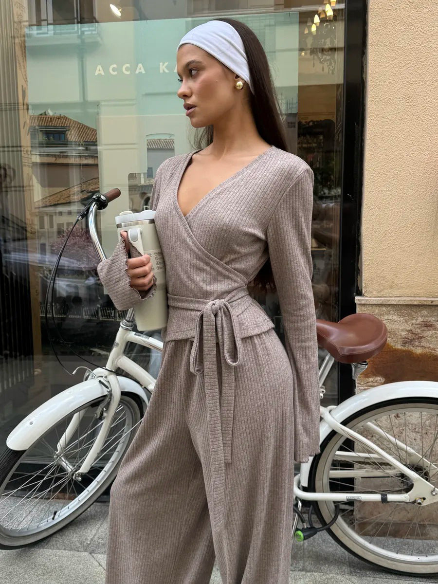 woman wearing oatmeal ribbed wrap crop top and wide leg pants posing beside bicycle