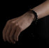 Hand wears black obsidian bracelet with tiger eye beads.