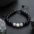 Black bracelet with three white marble-effect beads.