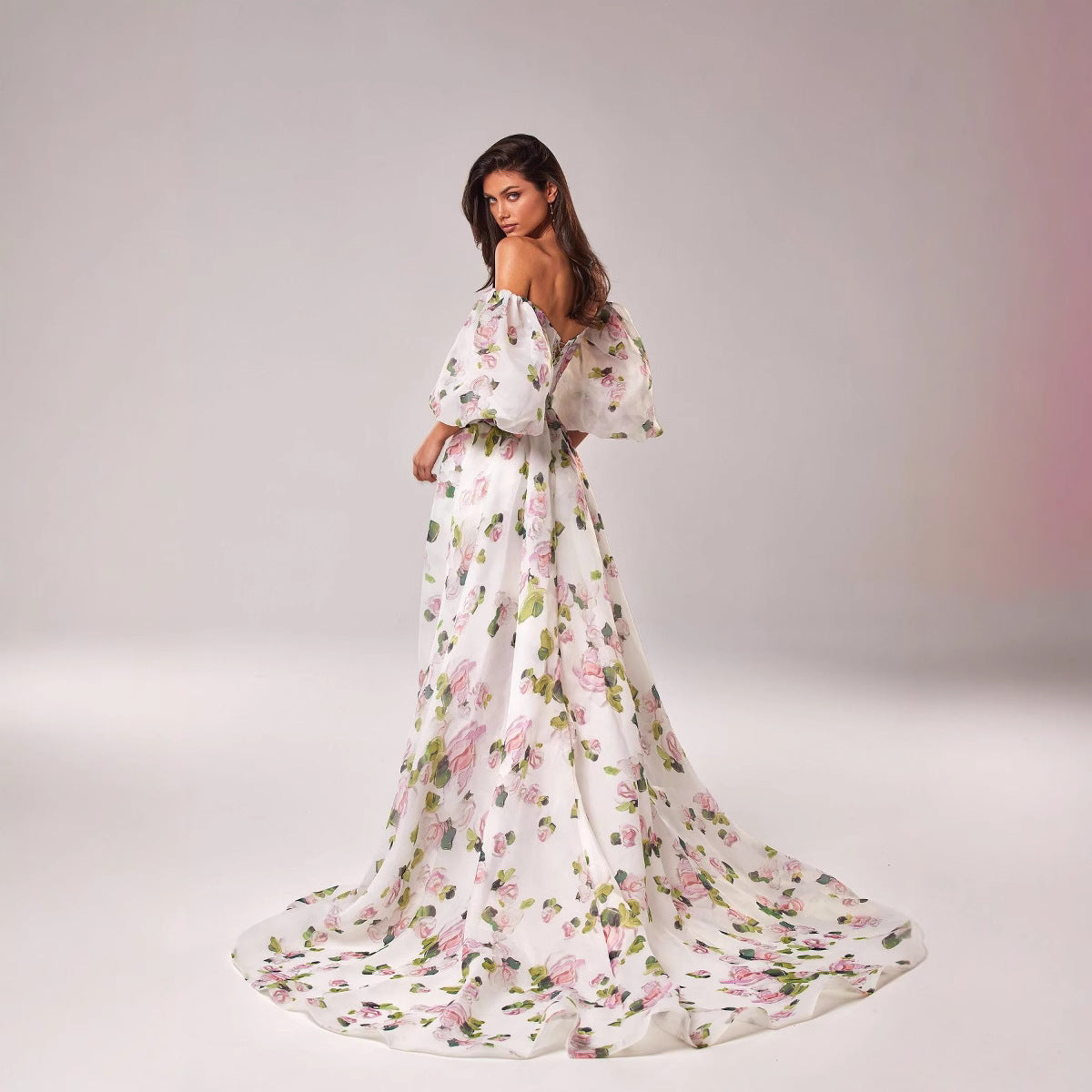 Woman wearing a off shoulder floral dress on a plain background