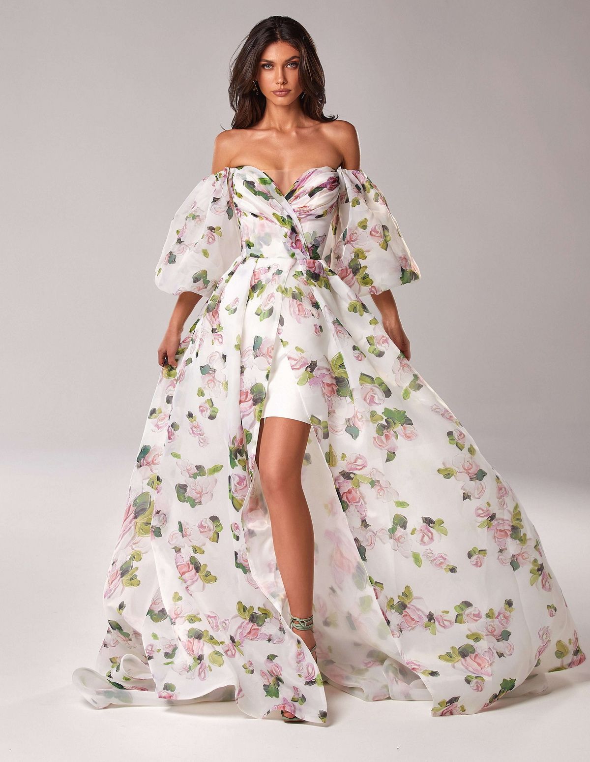Woman in pink off-shoulder puff sleeve floral gown with high slit and sweetheart neckline.