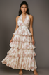Woman wearing an off-white floral tiered dress against a gray background