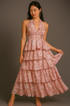 Woman wearing an old rose color halter  floral dress against a gray background