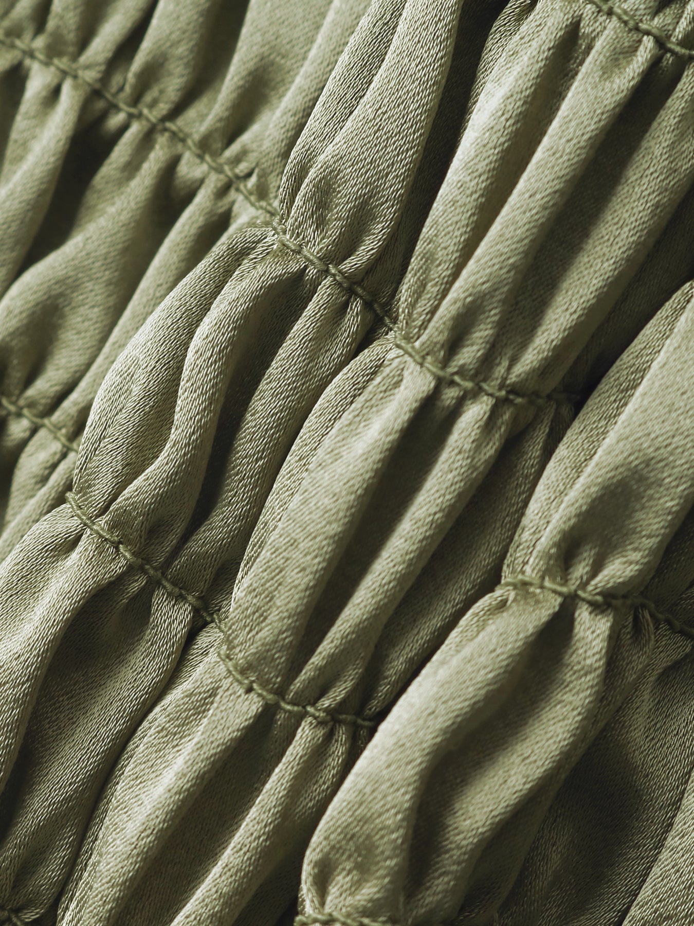 Close-up of ruched satin fabric texture in olive green