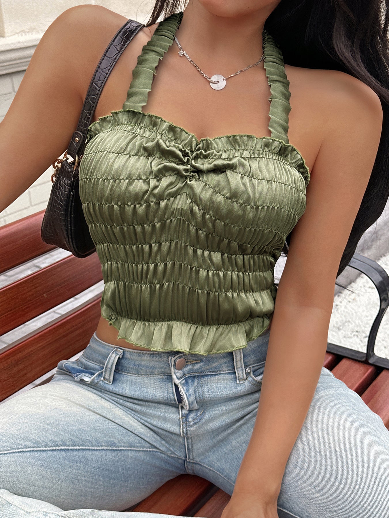 Woman sitting on bench in ruched olive satin halter top