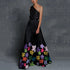 Woman wearing a black one-shoulder maxi dress with colorful floral patterns on a gray background