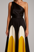 Close up of black one-shoulder dress with white and yellow geometric design on a gray background