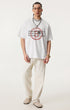 Man wearing white oversized t-shirt with Ouroboros 8-ball graphic and light sweatpants.