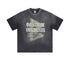 Flat lay of black graphic tee with 'Overcome Obstacles' text and taped triangle graphic.