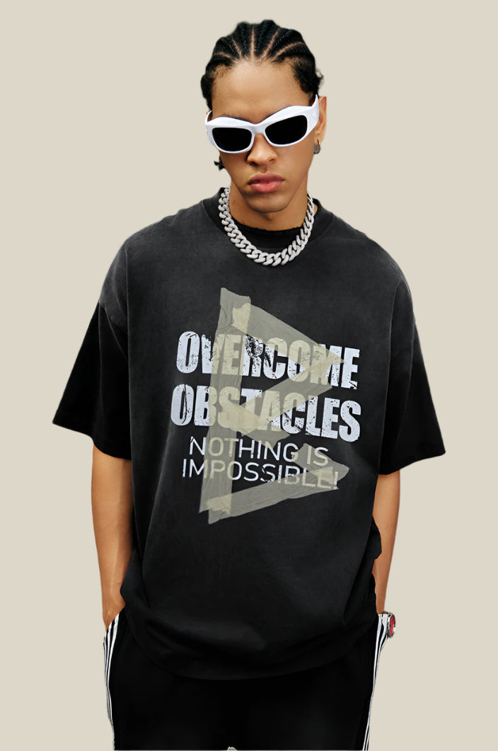 Man models a washed black T-shirt featuring cracked text print and yellow taped arrow overlaid.