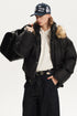 Three-quarter view of model wearing a black boxy winter jacket carrying a black duffel bag.