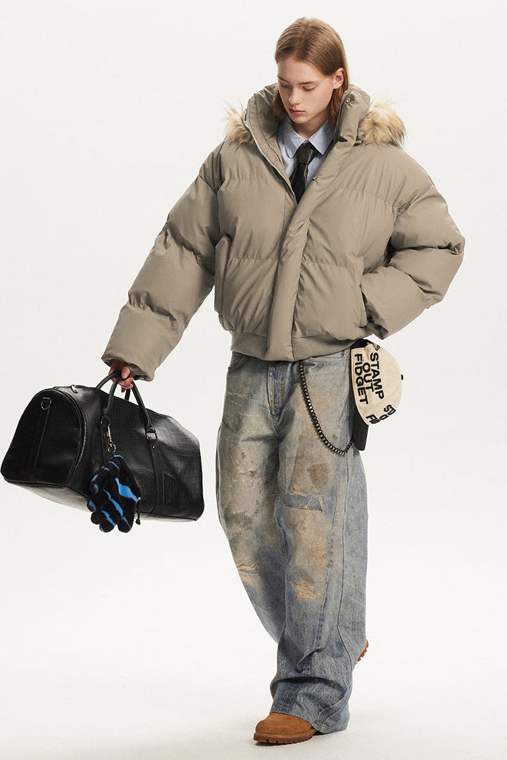 Front walking angle of a model in a khaki heavy winter puffer jacket carrying a black duffel bag.