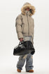 Side view of model wearing a khaki puffer jacket with the plush faux fur hood pulled completely over head.