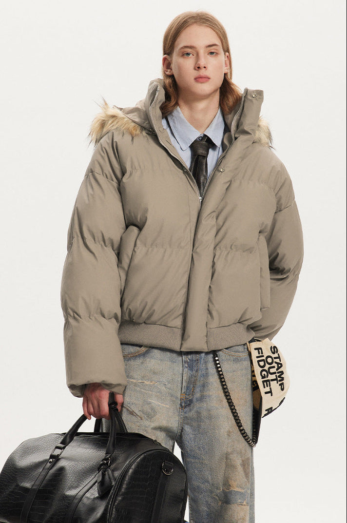 Medium shot of a model wearing a short khaki channel-quilted winter jacket with high neck closure.