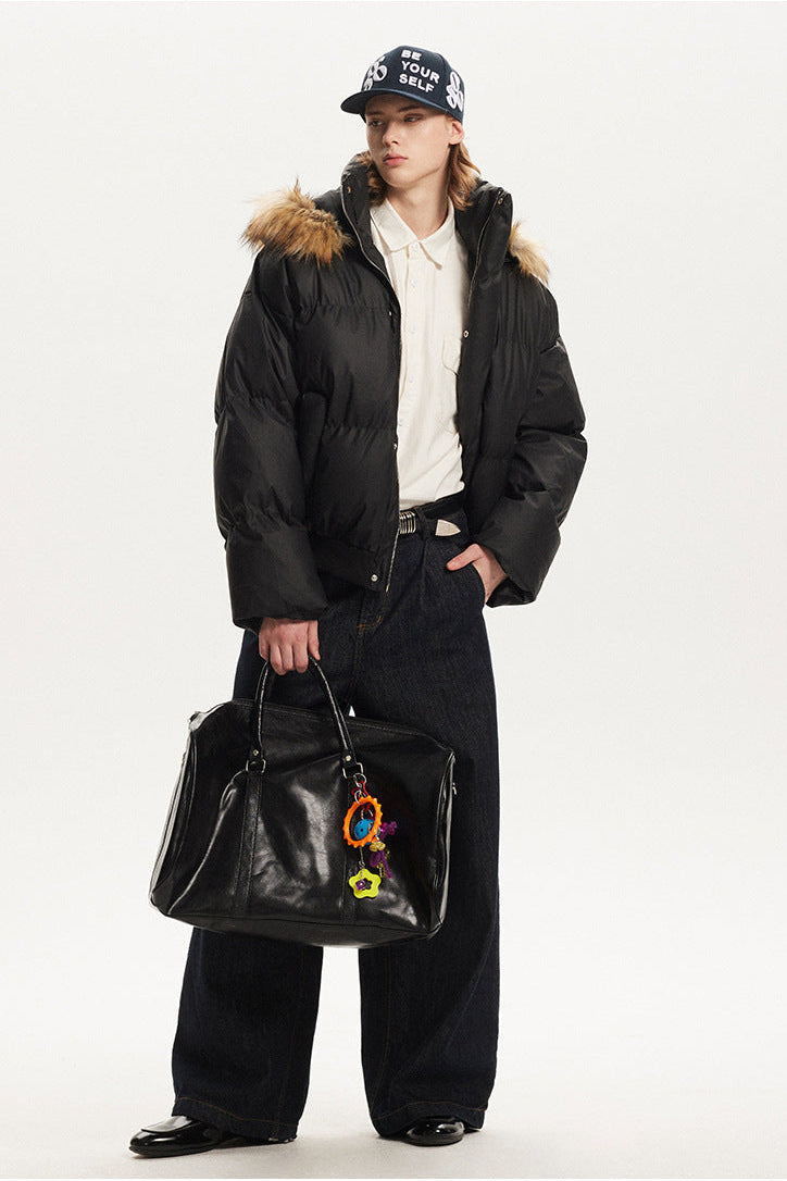 Full length view of model styled in a black oversized puffer jacket with brown fur hood trim.