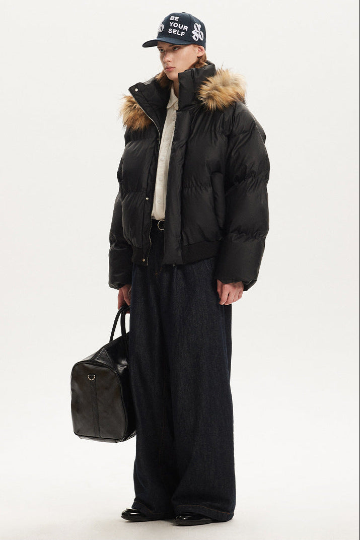 Profile angle of model wearing a black heavy winter parka coat with faux fur collar hood.
