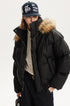 Close-up profile of model wearing a black puffer coat with high chin guard and faux fur trim.