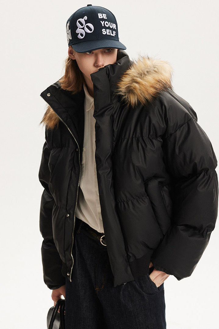 Close-up profile of model wearing a black puffer coat with high chin guard and faux fur trim.