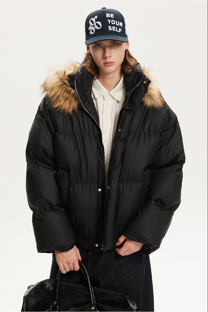 Front portrait view of a model in a black relaxed fit puffer coat with plush hood trim.