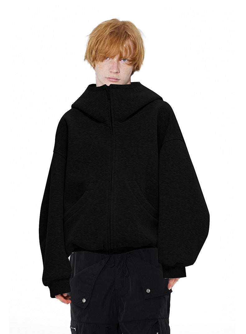 Front view of male model wearing classic black oversized zip up hoodie with high stand collar zipped up.