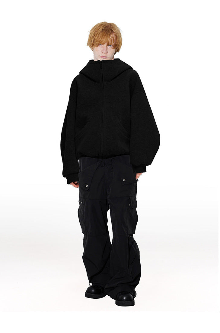 Full length view of male model in black high neck zip up hoodie jacket paired with black wide leg cargo pants.