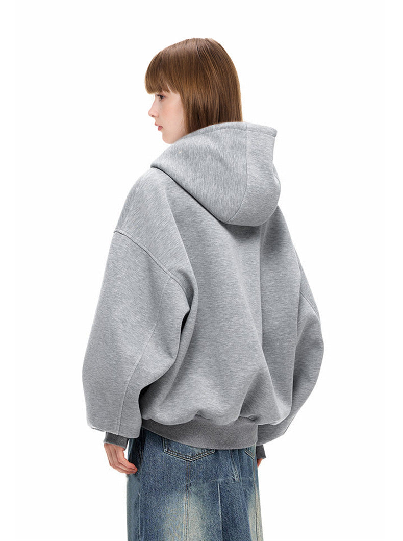 Back profile view of female model wearing loose heather gray full zip hoodie with wide hood and slouchy sleeves.