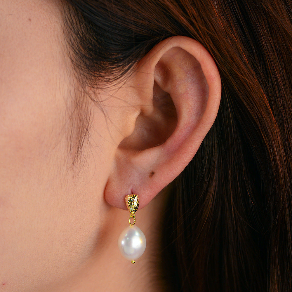 Gold-tone freshwater pearl drop earring worn on ear, side profile