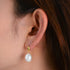 Silver-tone freshwater pearl drop earring worn on ear, side profile