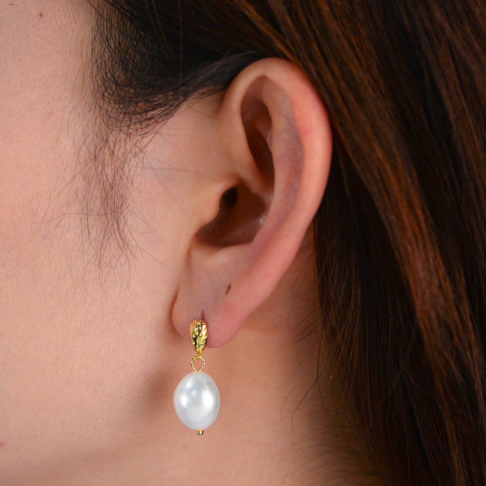Silver-tone freshwater pearl drop earring worn on ear, side profile