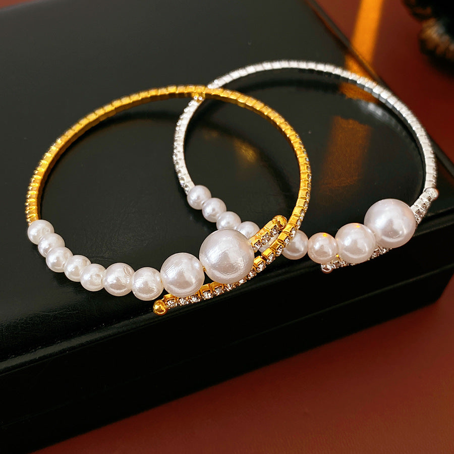 two pearl rhinestone open cuff bracelets in gold and silver displayed on a black box