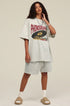Woman in light grey phonograph tee posing at an angle.