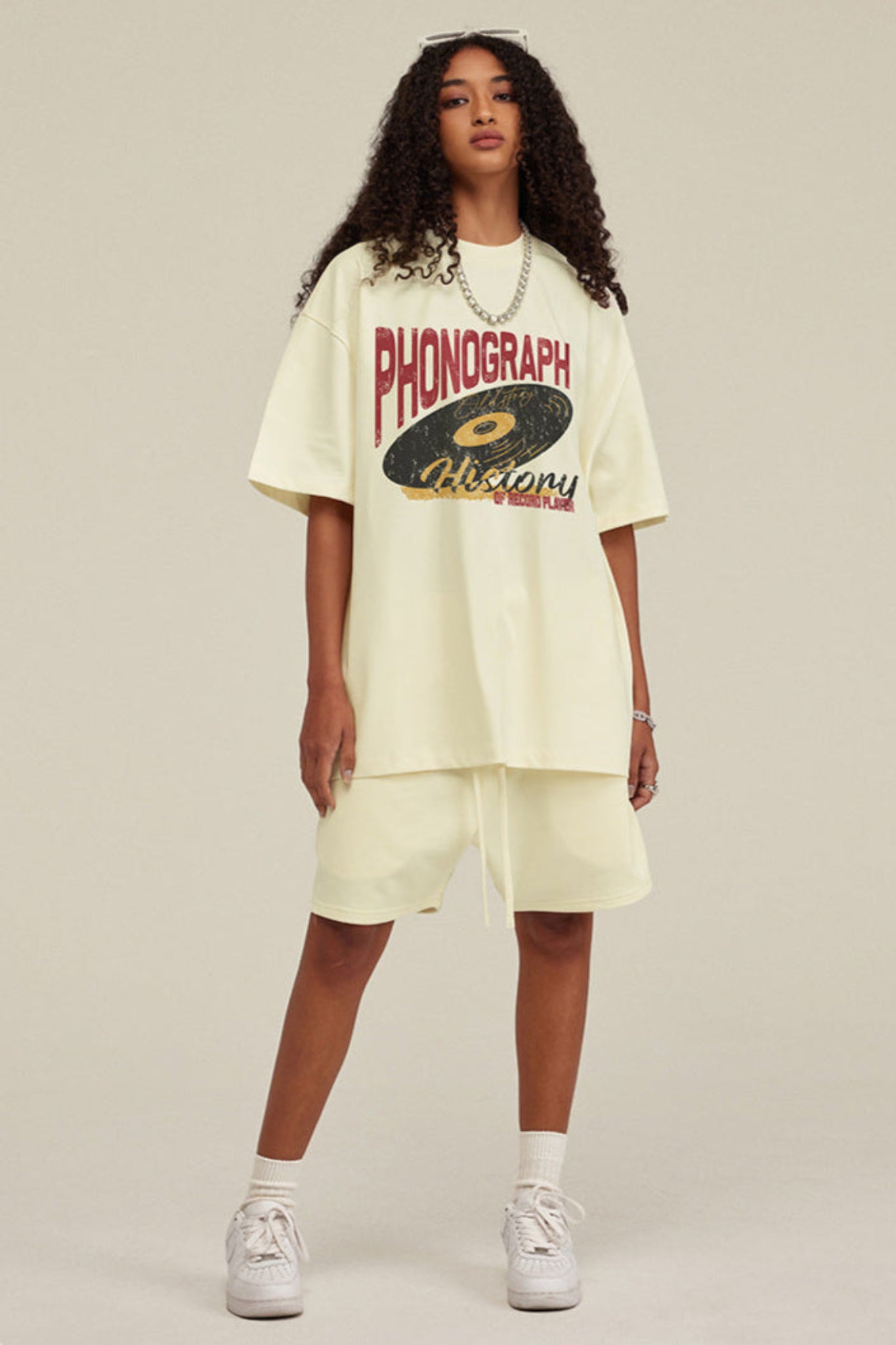  Full-body view of woman in light yellow phonograph tee.