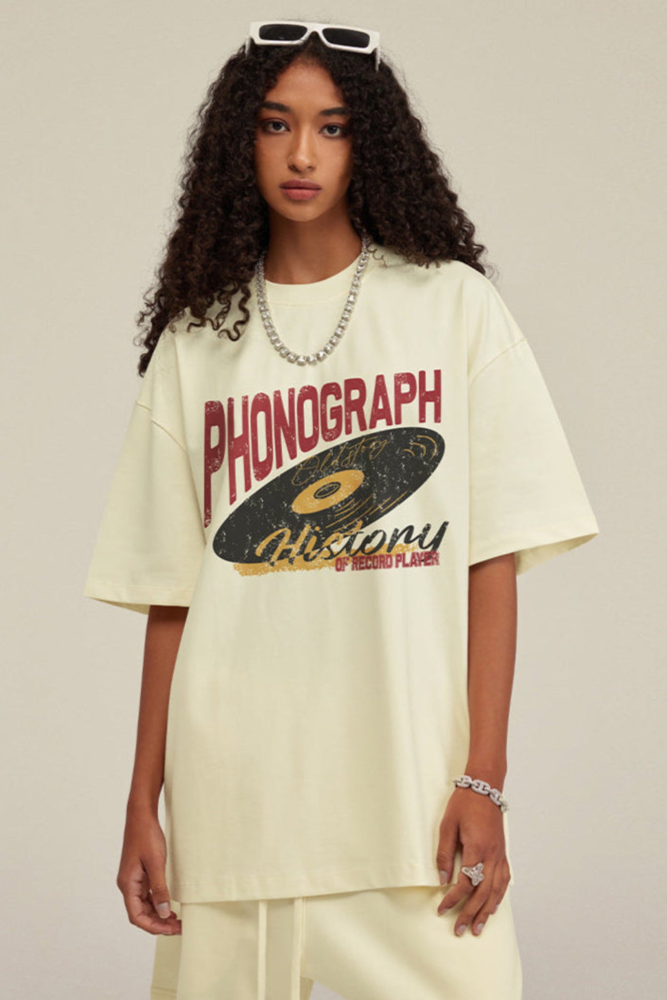 Woman in milk tea graphic tee with phonograph print and bold necklace.