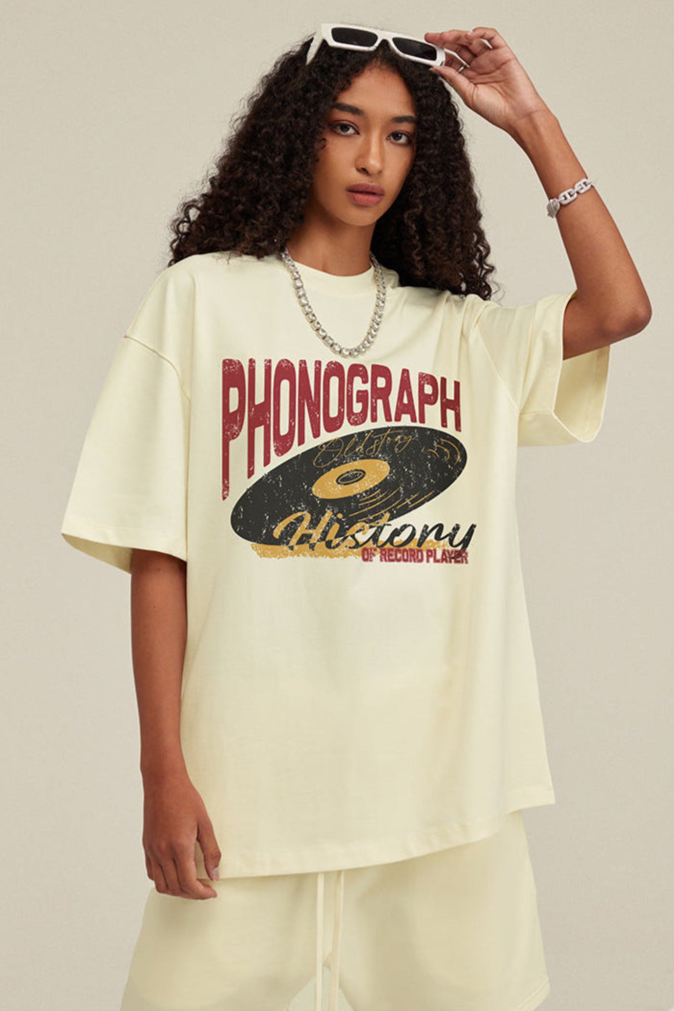 Model adjusts sunglasses while wearing oversized milk tea phonograph tee