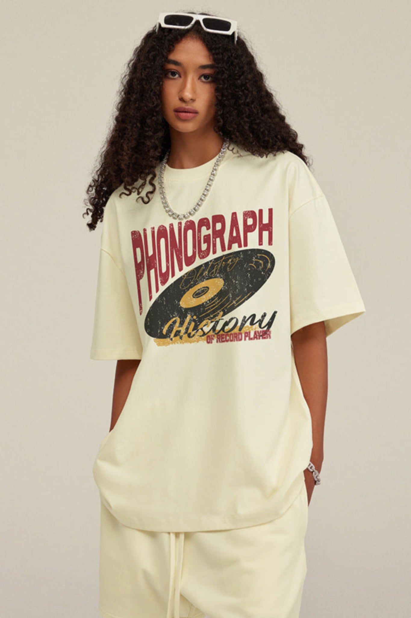 Woman poses with hands in pockets wearing phonograph print tee