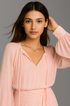 Close up of woman wearing a pink ruffle set against a gray background