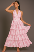 Woman wearing a pink tiered dress against a gray background