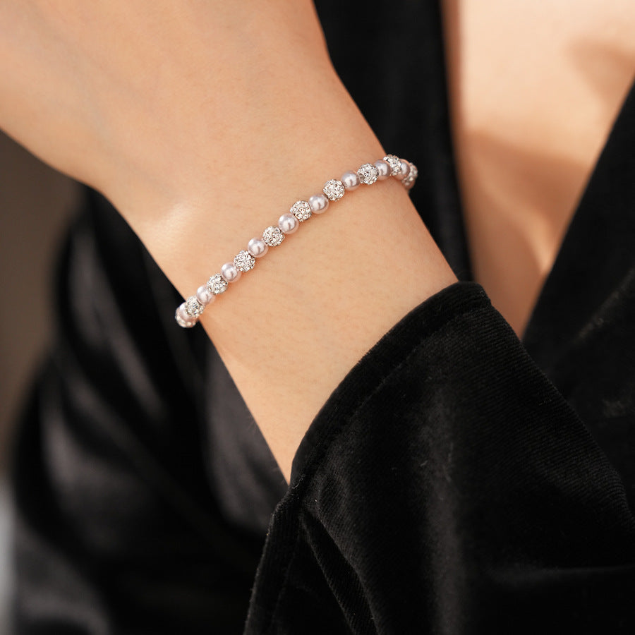 close-up of pink pearl beaded bracelet worn on wrist with black sleeve
