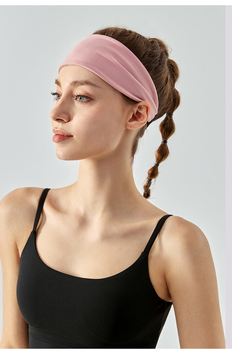 Woman wearing a wide light pink headband and black sports top, side profile.