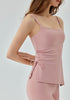 Woman wearing light pink yoga tank top with ruched drawstring side.