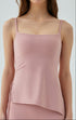 Woman in blush pink cooling tank top with asymmetrical hem and side strings.